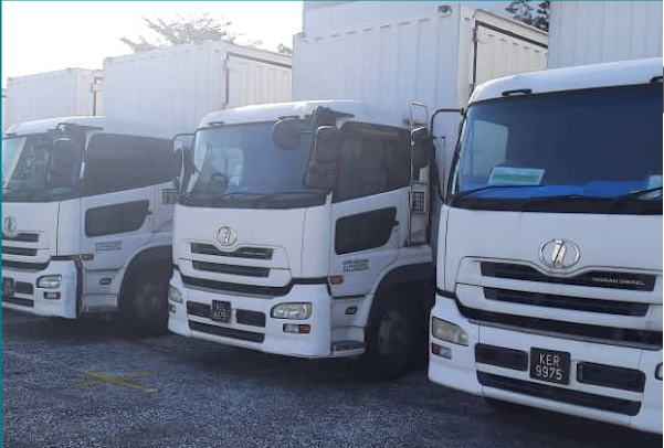 Three white commercial trucks parked side by side